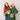 Una pareja sonriente con gorros navideños, el hombre recibe un regalo sorpresa mientras ella le cubre los ojos.